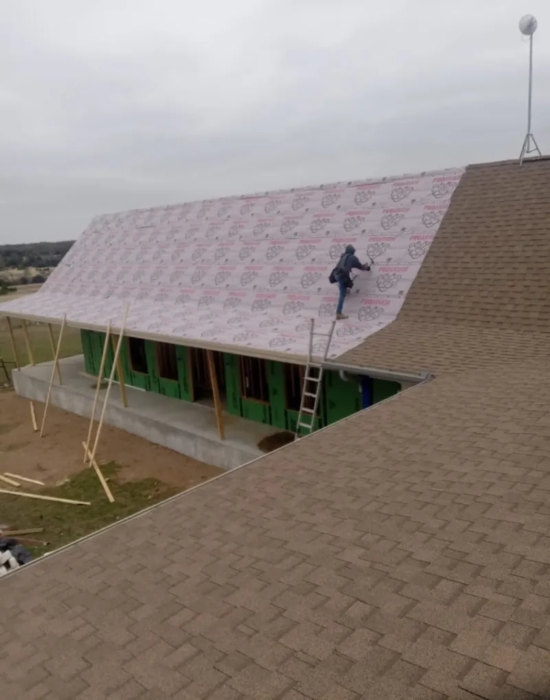 Worker preparing underlayment for a metal roof installation in Manchester